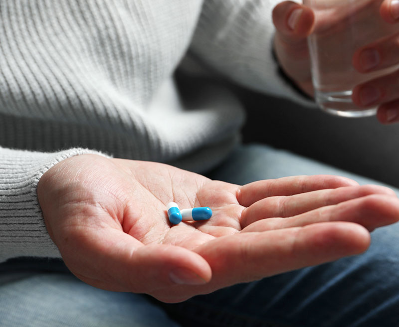 Women Holding Two Nirvana Detox Pills With A Glass of Water